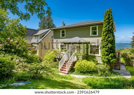 cute craftsman cottage mid century turn of the century set amongst lush green landscaping and gardens with beautiful blue sky front door stairs to entry pretty flowers