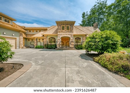 Large luxury home on golf course in Pacific Northwest estate with manicured landscaping bright blue skies whispy white clouds in the sky featuring front door entryway inviting views
