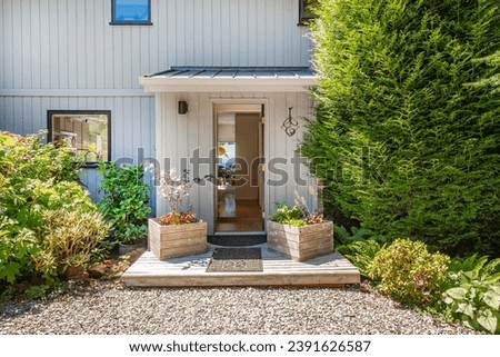 cute craftsman cottage mid century turn of the century set amongst lush green landscaping and gardens with beautiful blue sky front door stairs to entry pretty flowers