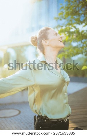 smiling modern female worker near business center in green blouse rejoicing. Royalty-Free Stock Photo #2391633885