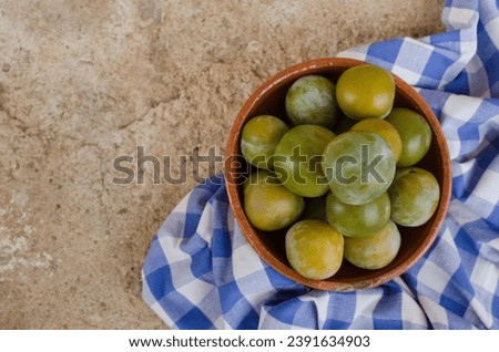 Ceramic bowl with fresh organic green plums just picked from the tree on a cloth. Horizontal still life with fruit photography. View from above. Healthy food and lifestyle concept. Copy space