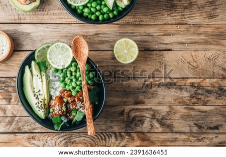 Buddha bowl with crispy sesame chicken asian style. Sweet and sour fried chicken with steamed rice, peas and acocado on rustic background. Healthy and balanced food concept. Top view with copy space Royalty-Free Stock Photo #2391636455
