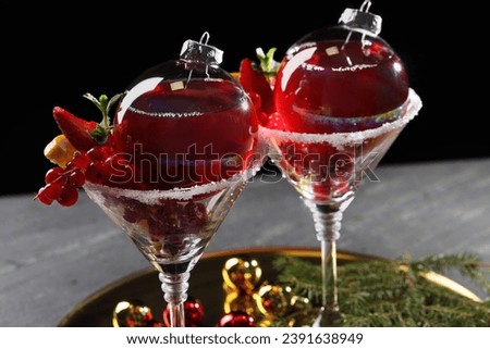 Creative presentation of Christmas Sangria cocktail in baubles and glasses on grey table against black background, closeup Royalty-Free Stock Photo #2391638949