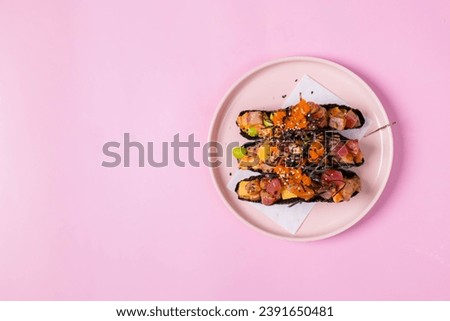 The image is a plate of healthy food on a pink pastel background. The plate is on a table and the food looks appetizing.
