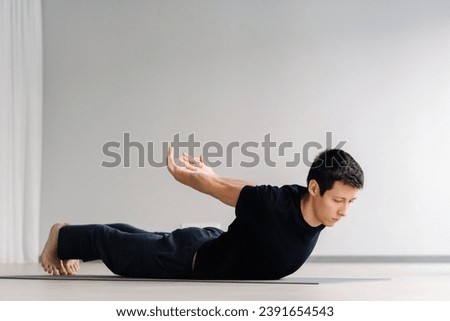 A man in a black T-shirt trains lying down doing stretches in the gym. Royalty-Free Stock Photo #2391654543