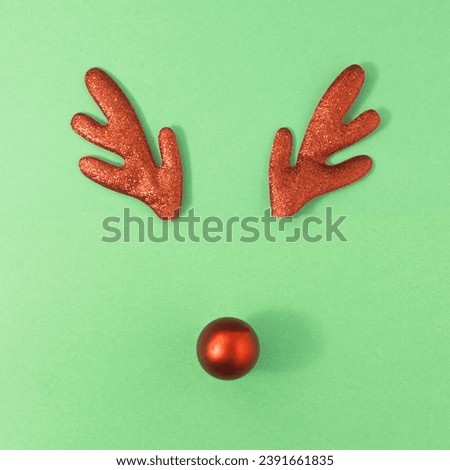 Reindeer antlers with christmas ball on green background. Christmas minimal Greeting card.