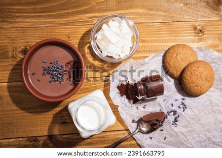 Chocolate panna cota with coconut milk, vegan chocolate pudding with agar-agar and extra-dark cocoa powder. Vegan milk, cocoa powder, coconut chips and dry lavender next to a delicious Italian dessert Royalty-Free Stock Photo #2391663795