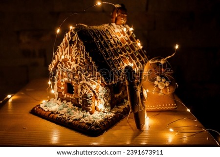 a gingerbread house in the role of a wedding cake decorated with a garland, gingerbread brides are standing next to it. Royalty-Free Stock Photo #2391673911