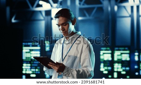 Proactive employee walking through data center electronics providing processing resources for different workloads. Organized engineer evaluating server rigs tasked with solving complex operations