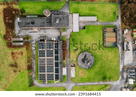 Aerial top down view on a small factory building and fresh green grass field around it. Clean ecology production concept. Keeping earth clean while producing products for mass production