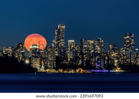 Waning 99.18% full moon (Buck Moon) rising from behind Downtown Vancouver, taken from West Vancouver, BC, Canada