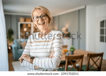 Portrait of one mature blonde caucasian woman with eyeglasses at home happy smile looking to the camera confident wear sweater in bright room copy space Royalty-Free Stock Photo #2391702011