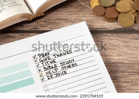 Handwritten Christian to-do list in notebook with money and open holy bible. Biblical concepts of prayer, giving thanks, tithing, study, caring and helping others, and joy in God Jesus Christ. Royalty-Free Stock Photo #2391704519