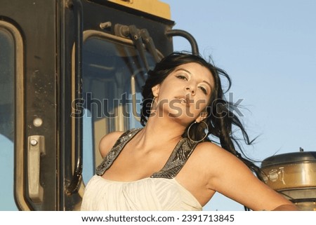 Photo of a beautiful Hispanic girl in a construction site near heavy machinery