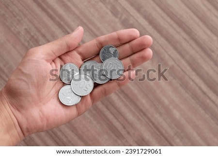 Man holding some coins. Pile of Indonesian rupiah coins.  Finance concept photograph