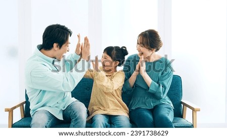 Asian family getting excited watching TV. Watching sports. Royalty-Free Stock Photo #2391738629