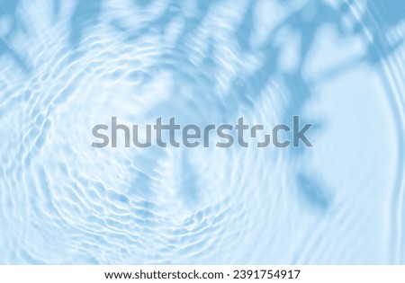 Background summer natural blue texture, clear water with ripples and splashes. Water waves in sunlight with leaf shadow, and background concept of cosmetics, moisturizer, and toner.