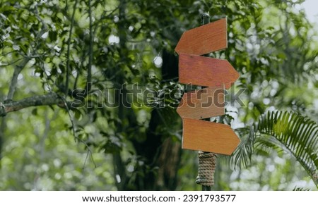 Blank wooden arrow sign on metal post in park. Template with empty information sign.