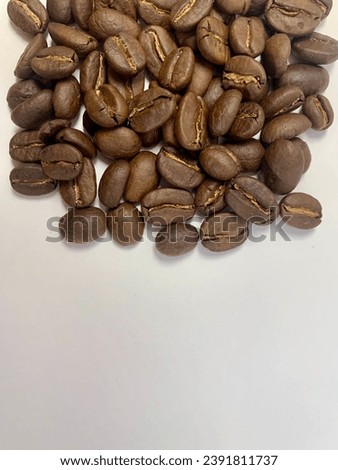 Large group of freshly roasted coffee beans on studio background. A large group of objects indoors: brown coffee, food, produce, roasted coffee beans. Royalty-Free Stock Photo #2391811737