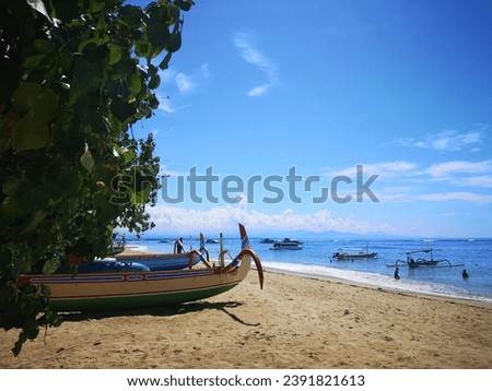 The picture of the balinese traditional fishing boat on the beach and in the sea with the blue sky and sunlight.