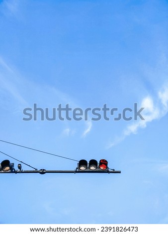A red traffic light is seen against a blue sky with a few wispy clouds.