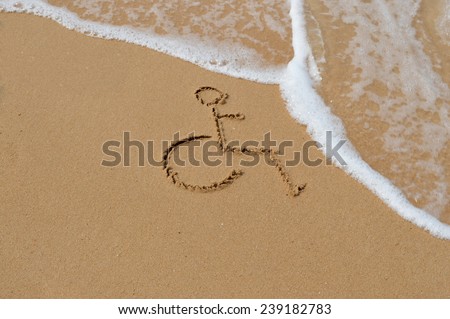 A disabled symbol is drawn in the sand at the beach