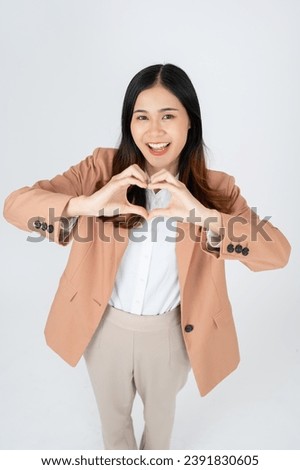 Beautiful smiling Asian businesswoman making heart shape hand sign on white isolated background.