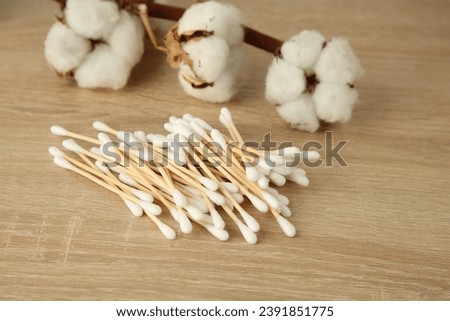 Cotton swabs and flowers on wooden table, closeup
