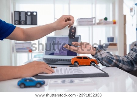 car dealer is handing over car keys to customer after sales contract and installment contract have been signed. Concept of handing over car keys to customers after the sales contract has been approved