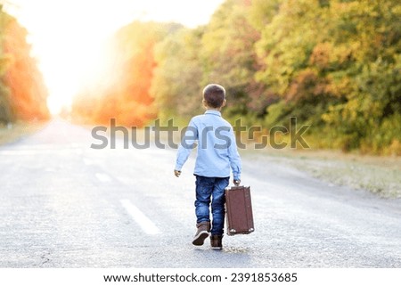 Happy child with a suitcase on the road in the park travel Royalty-Free Stock Photo #2391853685