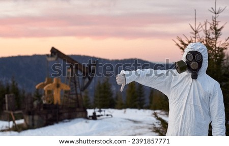 man wearing white coverall gas mask oil field oil pump jack