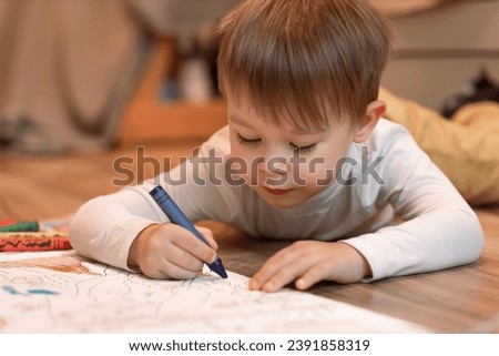 Cute child boy drawing with pencils in preschool 