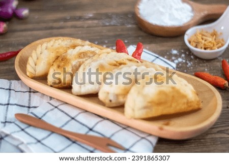 cireng ayam is a fried tapioca flour stuffed with chicken meat, ready to be eat. cireng served on board plate, napkin, flour, garlic, chili and wooden background. food advertising. ide jualan