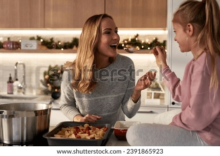 Caucasian mother and daughter tasting food before Christmas