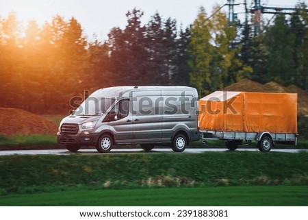 A Car and a Rental Trailer on a Curvy Road. A Smart Way to Move Your Stuff. Transporting Cargo with a Car and a Trailer. A Convenient and Cost-Effective Solution. Royalty-Free Stock Photo #2391883081