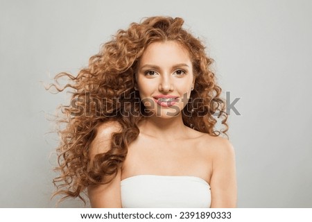 Good-looking young fashion model woman with natural makeup, clear skin and curly hairstyleposing on white background