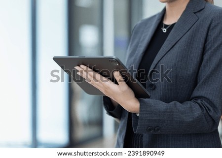 Portrait of Asian businesswoman using digital tablet standing in office workplace.