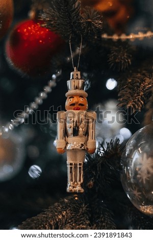 Festive decor, New Year winter details. Christmas tinny toy white Nutcracker hanging on the Christmas tree.