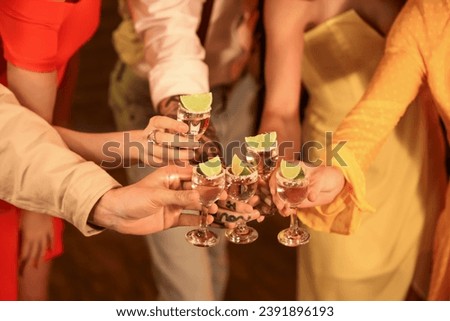Group of young friends with tequila shots in bar at night, closeup Royalty-Free Stock Photo #2391896193