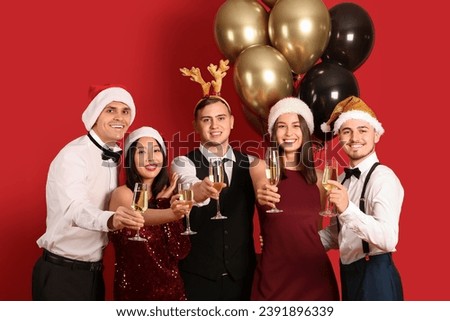 Group of friends with champagne on red background. New Year celebration