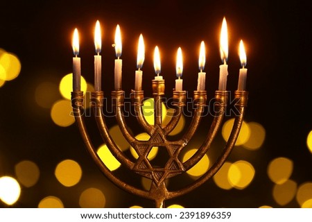 Menorah with burning candles for Hanukkah celebration against blurred lights, closeup