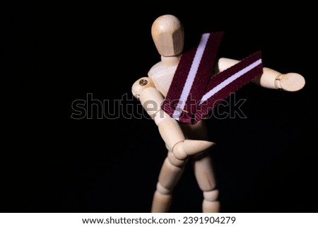 Portrait of a wooden man. Latvian flag on a black and white background. Soft selective focus. Artificially created grain for the picture.