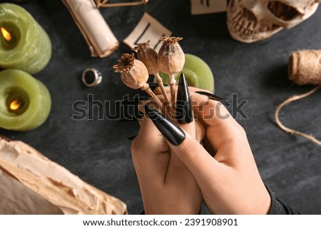 Witch with dried flowers on dark table, closeup