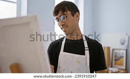 Confident, smiling young hispanic man enjoying a drawing lesson, a handsome artist's portrait in his cozy studio, mastering artistry and creativity with fun