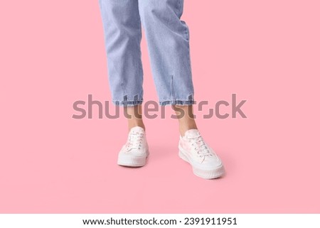 Legs of young woman in stylish white sneakers on pink background Royalty-Free Stock Photo #2391911951