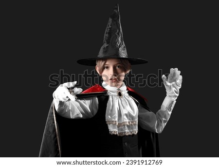 Little actor dressed as magician on dark background