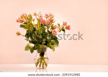 A bouquet in a transparent vase of apricot-colored  bouquet roses, color of the year 2024 peach fuzz, buds open flowers, pantone 2024