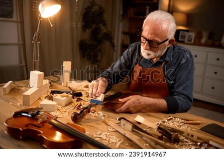 Senior carpenter craftsman making violin instrument Royalty-Free Stock Photo #2391914967