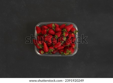 fresh strawberries on black background in plastic tray
