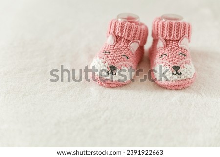 Pink knitted baby socks, booties on a white background with copy space. Pregnancy and motherhood concept, first birthday banner, handmade socks, baby warm clothes, handmade knitted socks, hobby Royalty-Free Stock Photo #2391922663